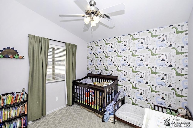 bedroom featuring light colored carpet, a ceiling fan, vaulted ceiling, a crib, and baseboards