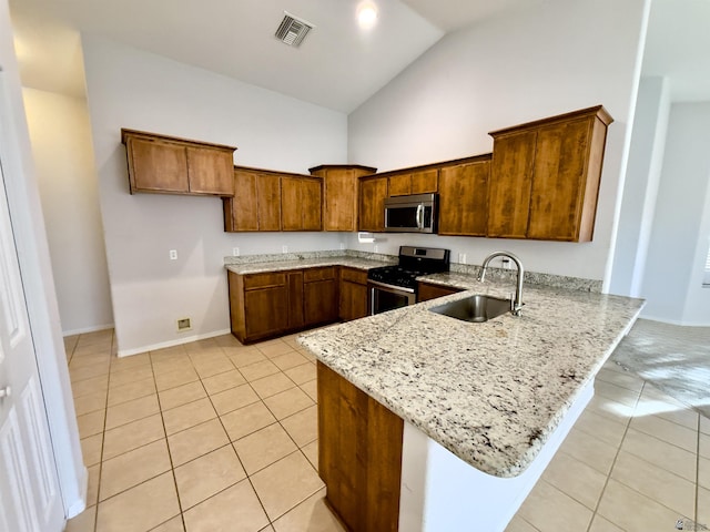 kitchen with brown cabinets, stainless steel appliances, visible vents, a sink, and light stone countertops