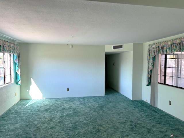 spare room featuring carpet and a textured ceiling