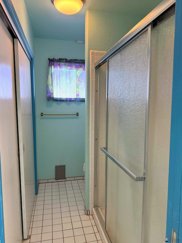 bathroom featuring tile patterned floors, a shower with shower door, and toilet