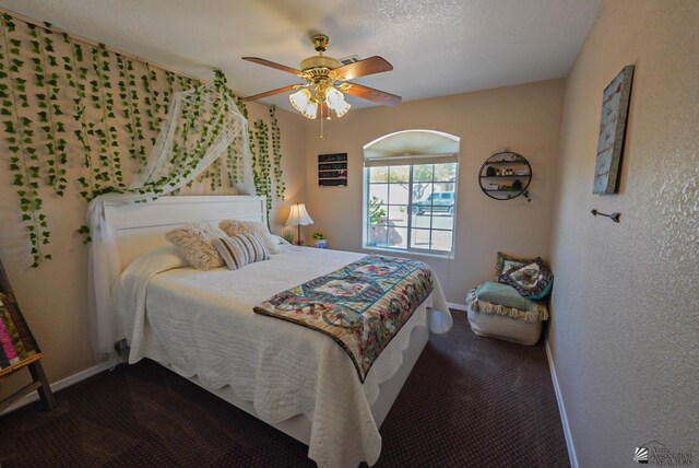 carpeted bedroom featuring a textured wall, baseboards, and ceiling fan