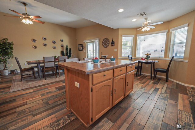 kitchen with visible vents, a center island, baseboards, and dark wood-style flooring