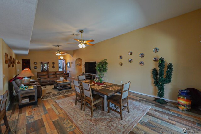 dining space with a ceiling fan, visible vents, wood finished floors, baseboards, and arched walkways