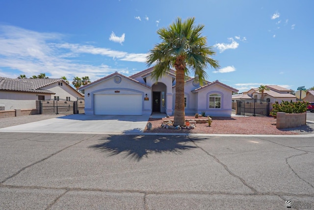 mediterranean / spanish home with a gate, stucco siding, driveway, and fence