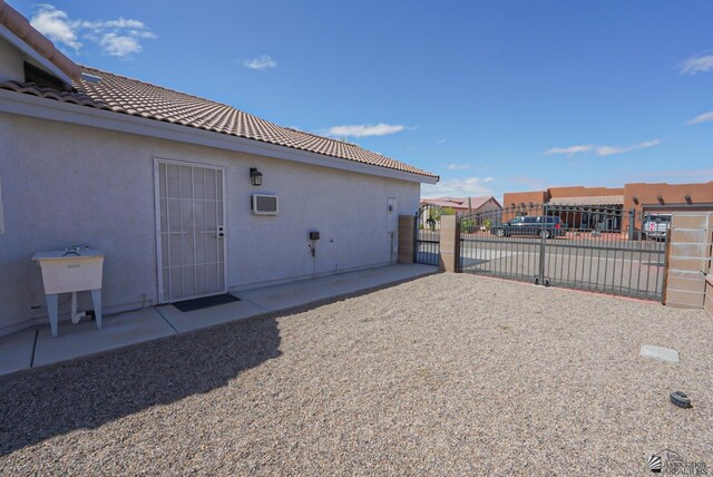 exterior space featuring fence, a tile roof, stucco siding, driveway, and a gate