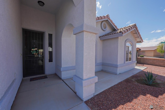 entrance to property featuring a tiled roof and stucco siding