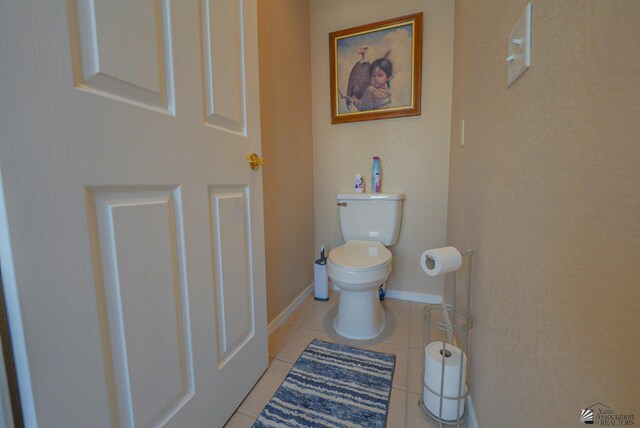 bathroom with tile patterned floors, toilet, and baseboards