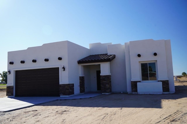 pueblo revival-style home featuring a garage