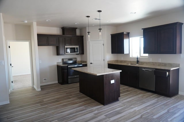 kitchen with sink, light hardwood / wood-style floors, decorative light fixtures, a kitchen island, and stainless steel appliances