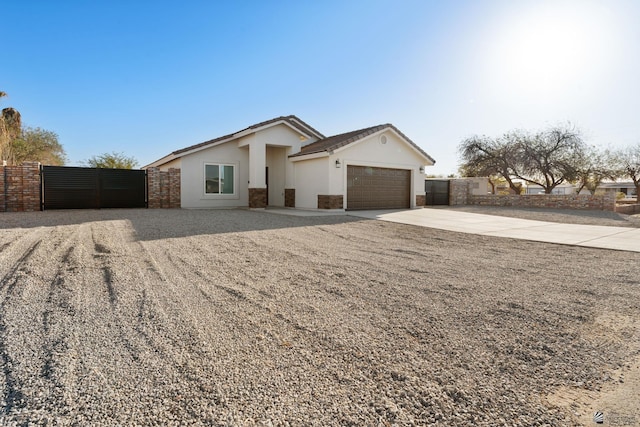 view of front of home with driveway, an attached garage, fence, and a gate