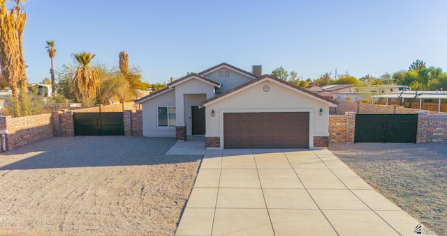 view of front facade with stucco siding, fence, concrete driveway, and a gate