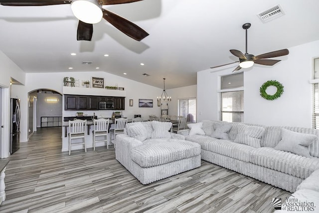 living room with vaulted ceiling and ceiling fan with notable chandelier