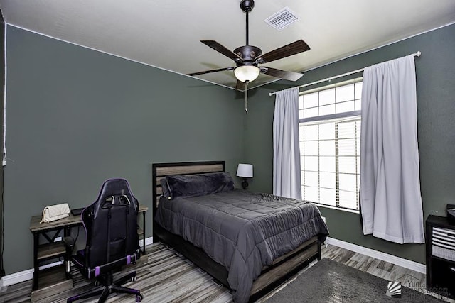 bedroom featuring multiple windows, hardwood / wood-style flooring, and ceiling fan