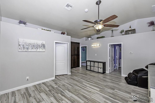 empty room with vaulted ceiling, ceiling fan, and light wood-type flooring