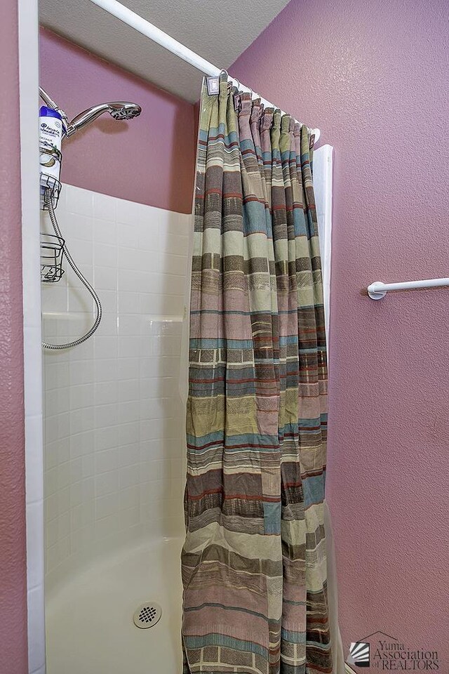 bathroom with a shower with curtain and a textured ceiling