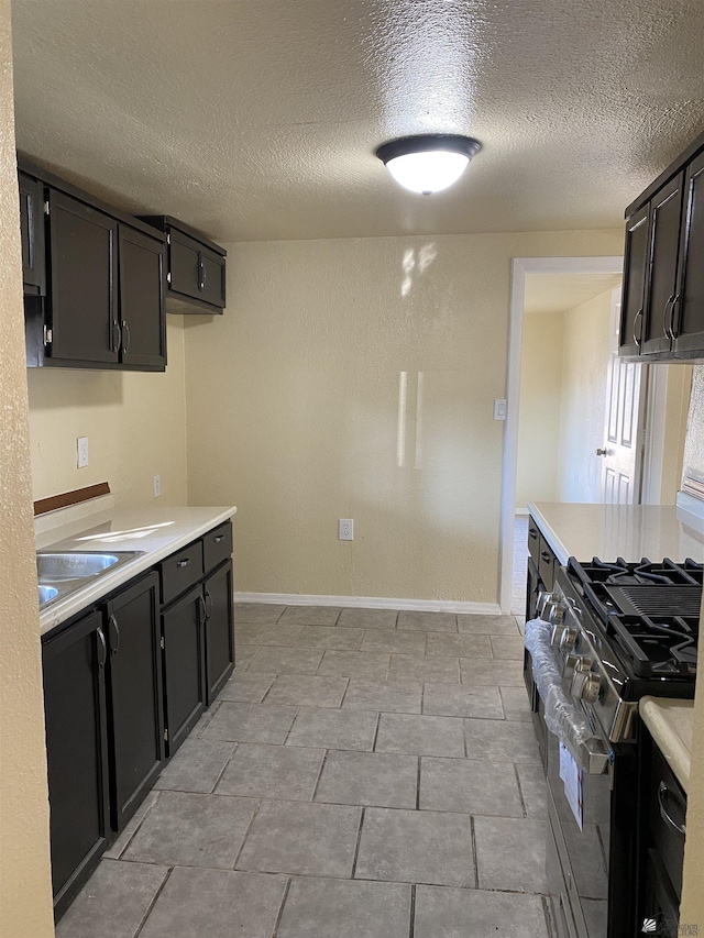 kitchen featuring sink, a textured ceiling, and gas range oven