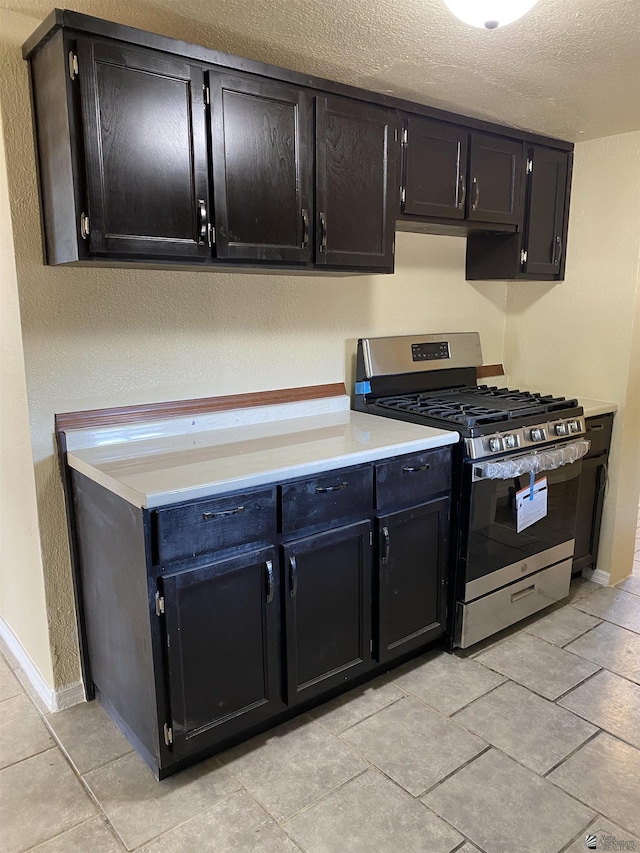 kitchen featuring stainless steel range with gas stovetop, a textured ceiling, and light tile patterned floors