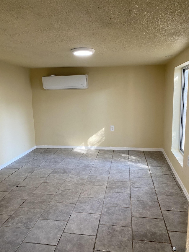 tiled spare room featuring an AC wall unit and a textured ceiling