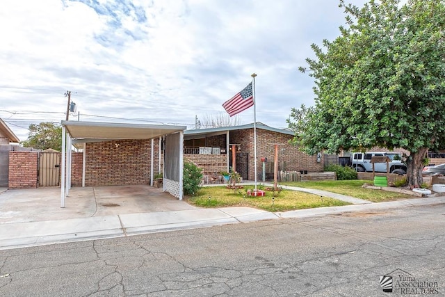 view of front of property featuring fence, a front lawn, a carport, and brick siding