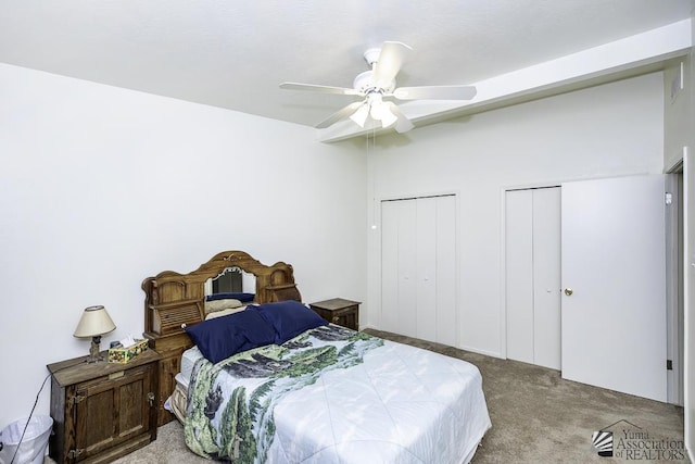 carpeted bedroom featuring ceiling fan and two closets