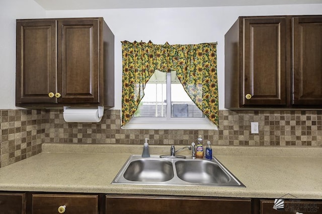 kitchen featuring sink, dark brown cabinets, and backsplash