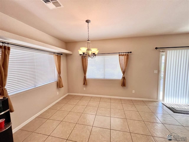 tiled empty room with an inviting chandelier