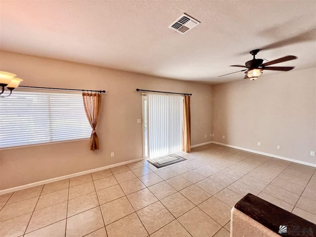 empty room with light tile patterned floors, a textured ceiling, and ceiling fan