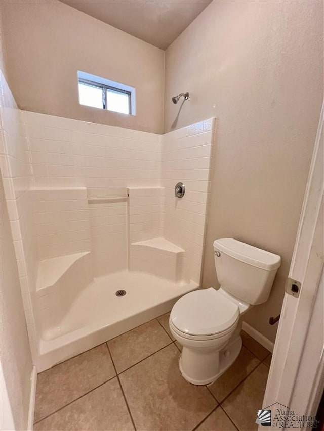 bathroom with tile patterned floors, toilet, and a shower