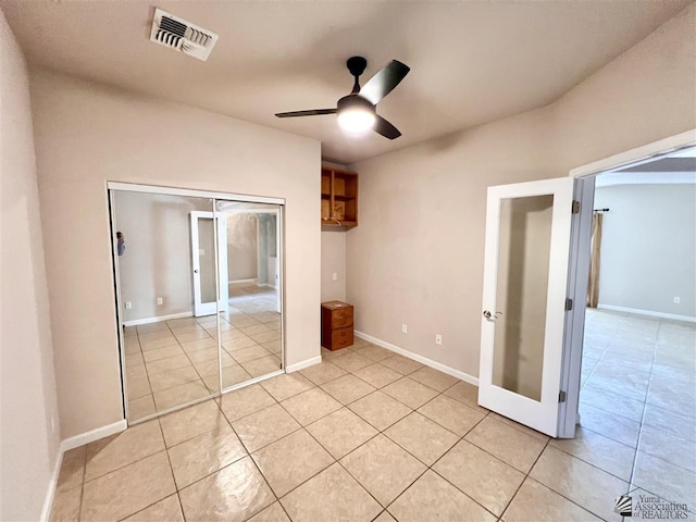 unfurnished bedroom with ceiling fan, light tile patterned flooring, french doors, and a closet