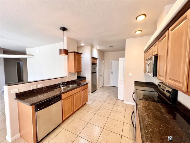 kitchen featuring sink, hanging light fixtures, dark stone countertops, light tile patterned floors, and stainless steel appliances