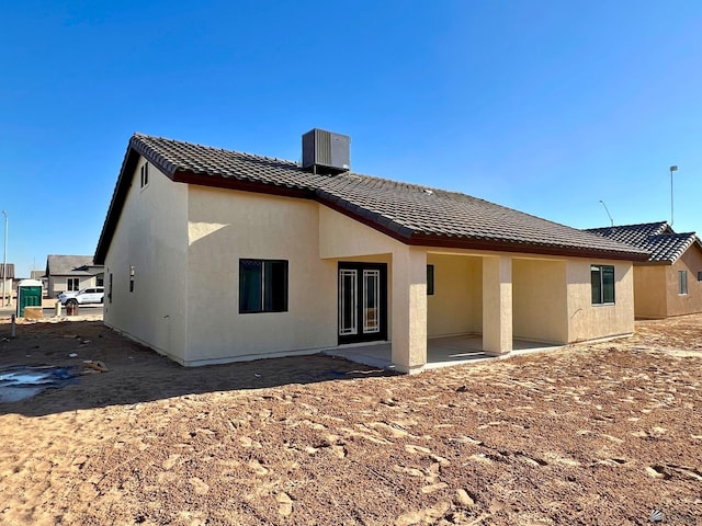 back of property with central AC and a patio