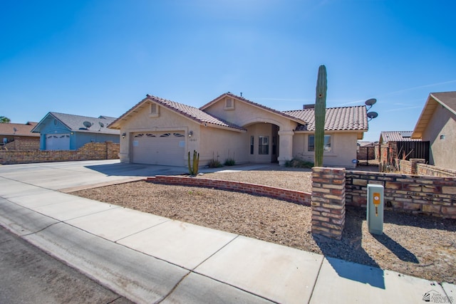 mediterranean / spanish-style home featuring concrete driveway, a tile roof, an attached garage, and stucco siding