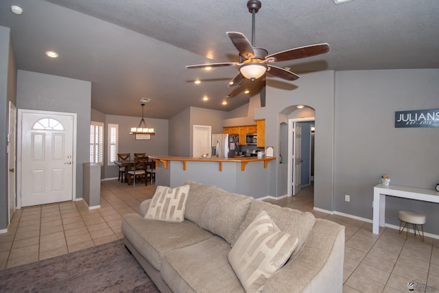 living area featuring arched walkways, baseboards, lofted ceiling, ceiling fan, and light tile patterned flooring