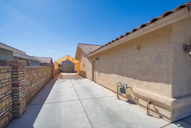 view of patio / terrace featuring a storage unit, an outdoor structure, and fence