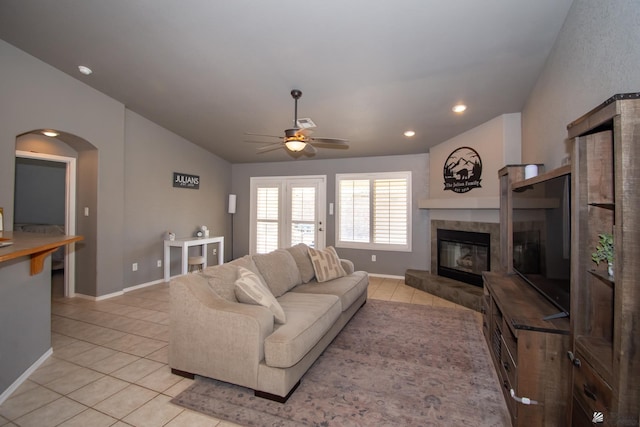 living area with light tile patterned floors, a ceiling fan, a tiled fireplace, lofted ceiling, and recessed lighting