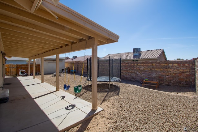 view of patio / terrace with an outbuilding, a storage unit, a trampoline, and a fenced backyard