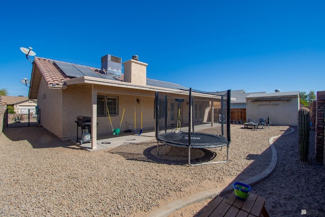 back of property with a trampoline, a fenced backyard, a patio, and stucco siding