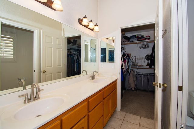 full bath featuring double vanity, tile patterned flooring, a sink, and a walk in closet