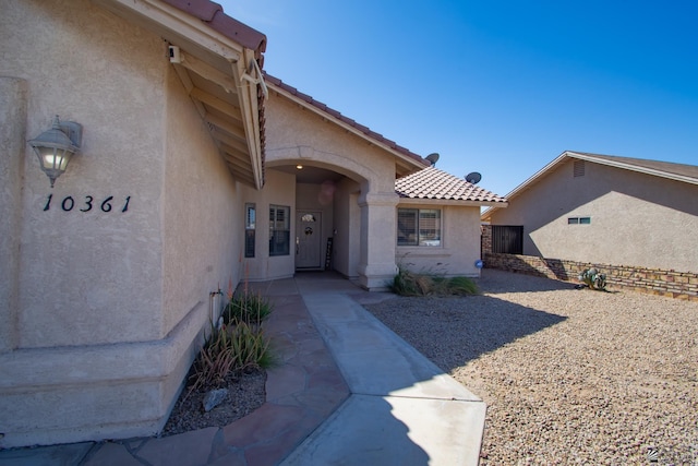 entrance to property with a tile roof and stucco siding