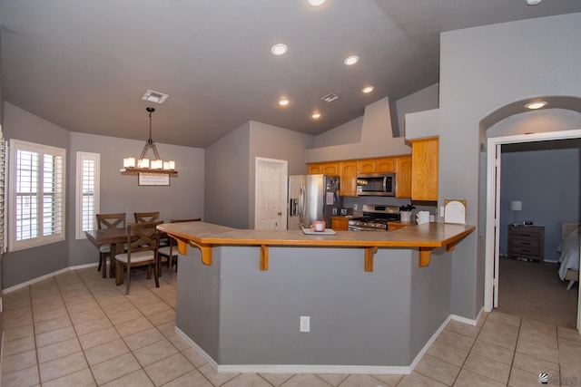 kitchen with light tile patterned floors, a breakfast bar area, stainless steel appliances, a peninsula, and visible vents