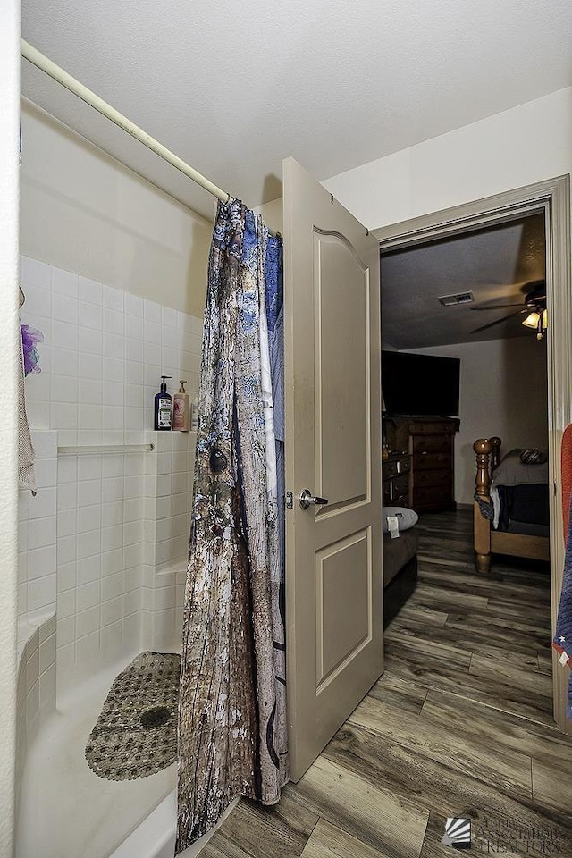 bathroom featuring walk in shower, ceiling fan, and hardwood / wood-style flooring