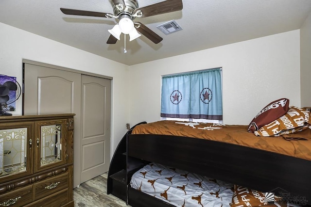 bedroom with a closet, light hardwood / wood-style flooring, and ceiling fan