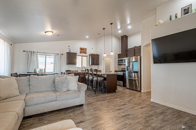 living room with wood-type flooring, high vaulted ceiling, and sink