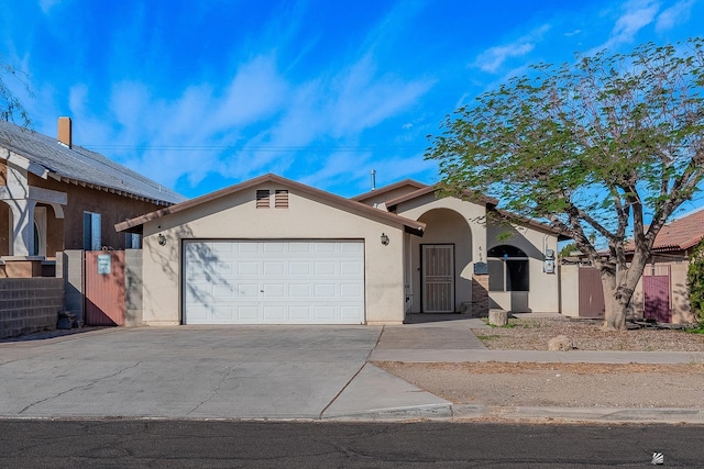 view of front facade with a garage, driveway, fence, and stucco siding