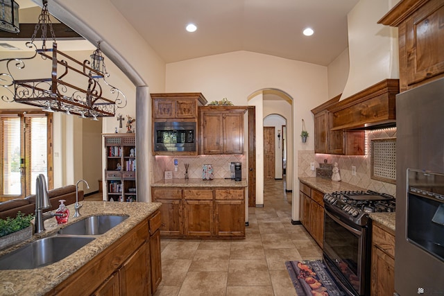 kitchen with sink, stainless steel appliances, premium range hood, lofted ceiling, and decorative light fixtures