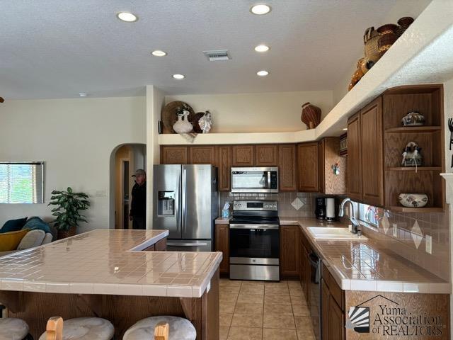 kitchen with visible vents, arched walkways, appliances with stainless steel finishes, open shelves, and a sink