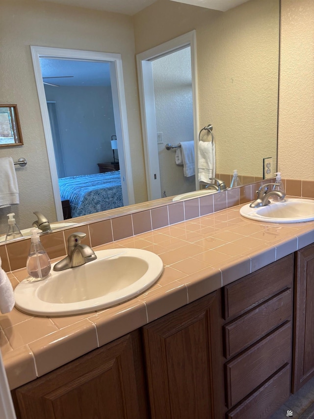 ensuite bathroom featuring connected bathroom, a sink, and double vanity