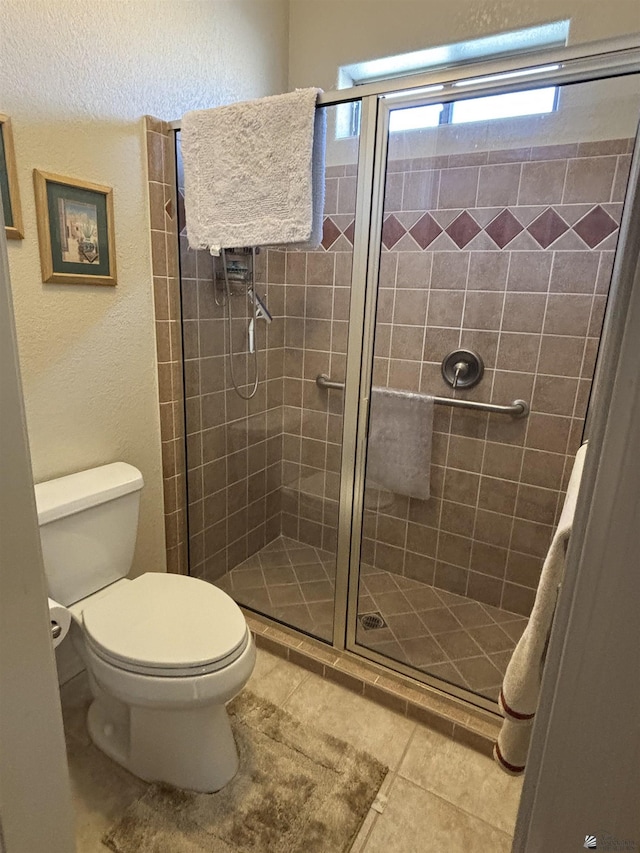 full bath featuring a stall shower, tile patterned flooring, and toilet