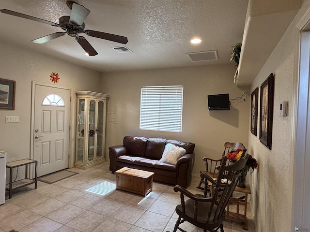 living area featuring visible vents, ceiling fan, and a textured ceiling