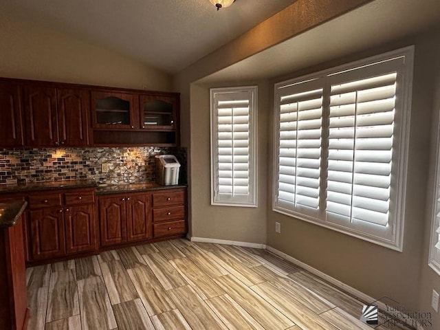 kitchen featuring decorative backsplash, dark brown cabinets, light hardwood / wood-style floors, and lofted ceiling